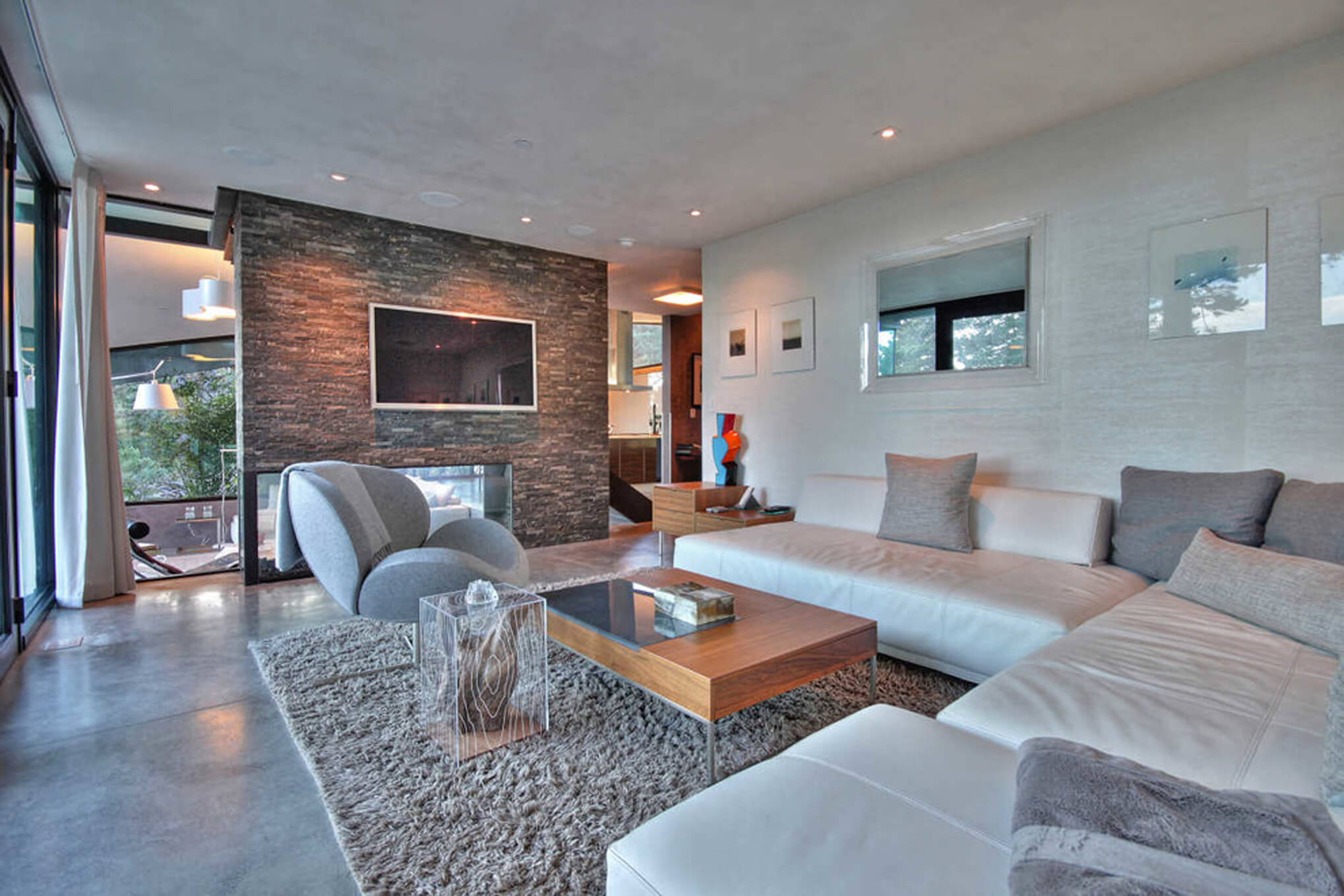 Informal living room with natural stone textures and sweeping views of the coast by Interior Designer, RM Interiors.