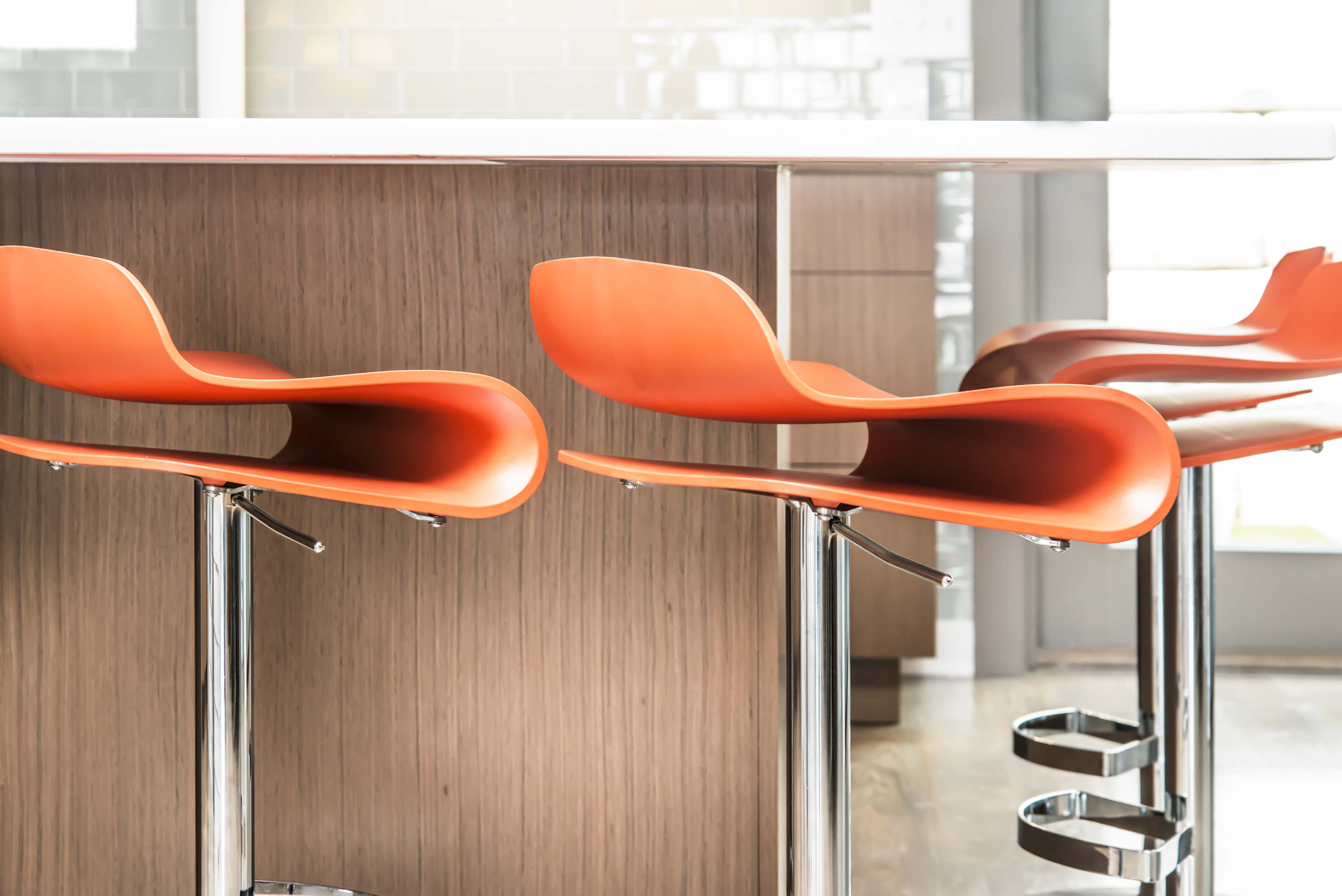 Detail shot of modern orange stools in a contemporary kitchen. Designed by Cincinnati Interior Designer, RM Interiors.