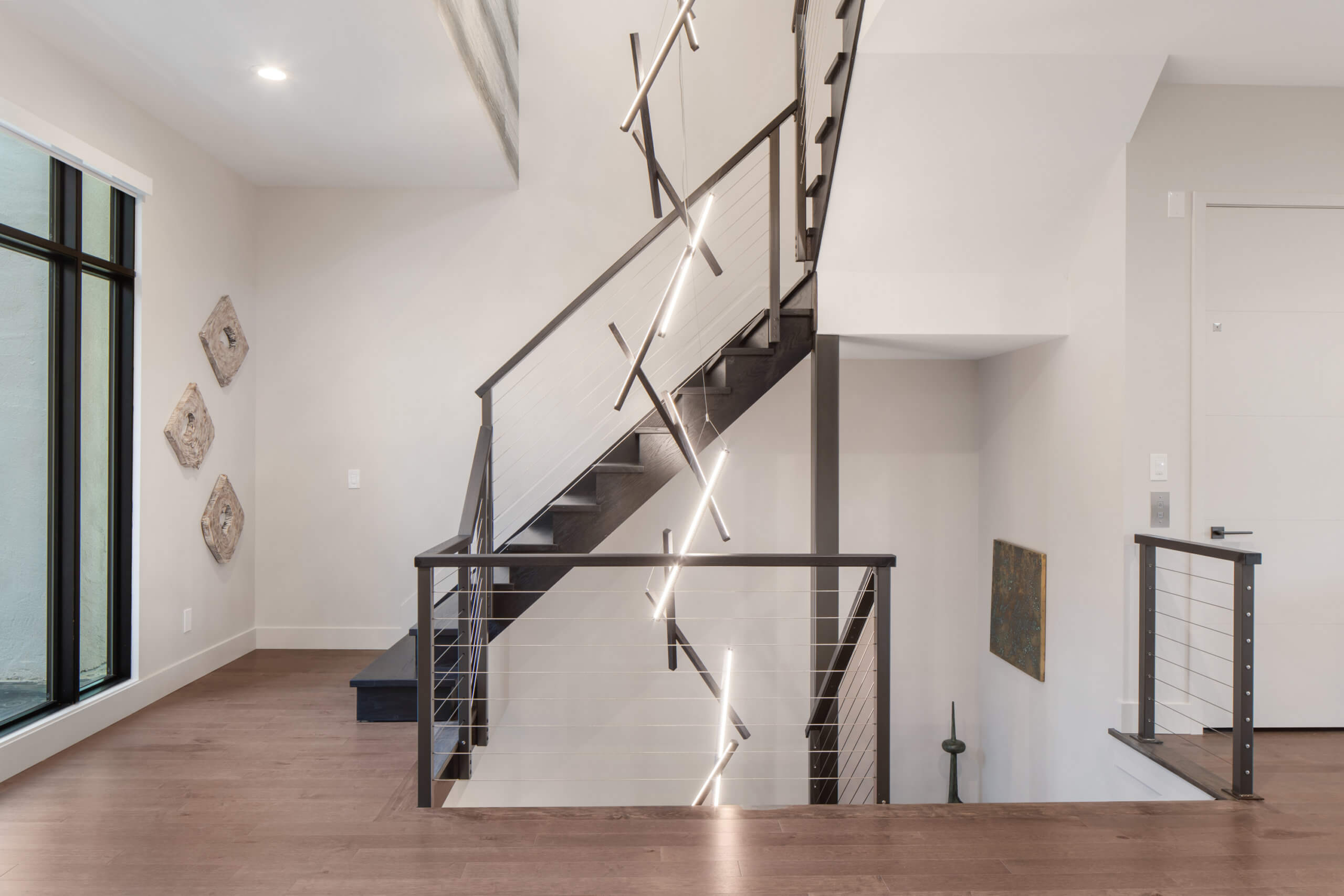 Open stairway features a custom 3 story tall chandelier. Lighting design and interiors designed by Cincinnati's premiere contemporary interior designer, Renan Menninger.