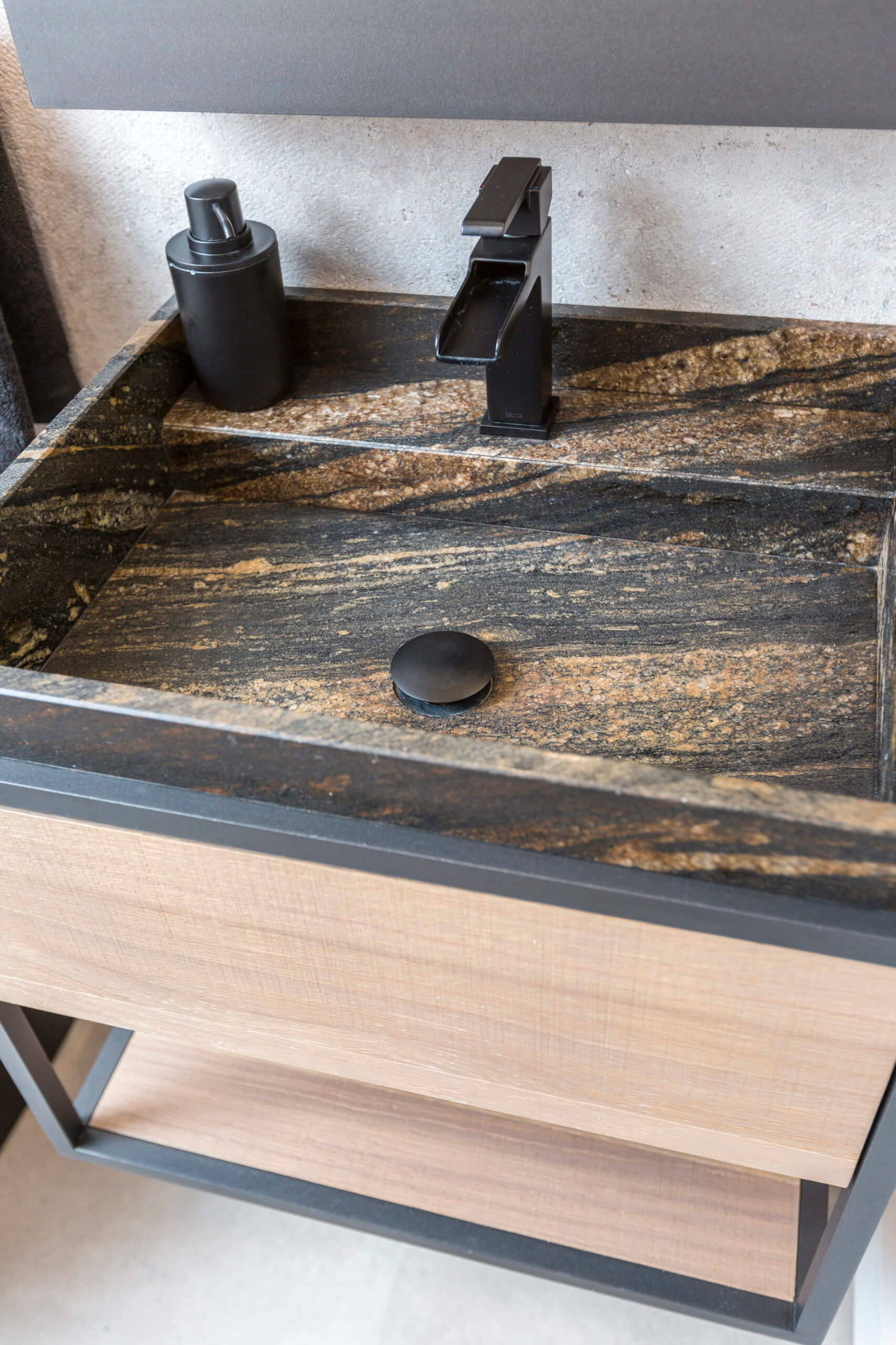 Closeup of custom designed natural stone sink with a custom natural wood vanity designed by Cincinnati interior designer, RM Interiors.