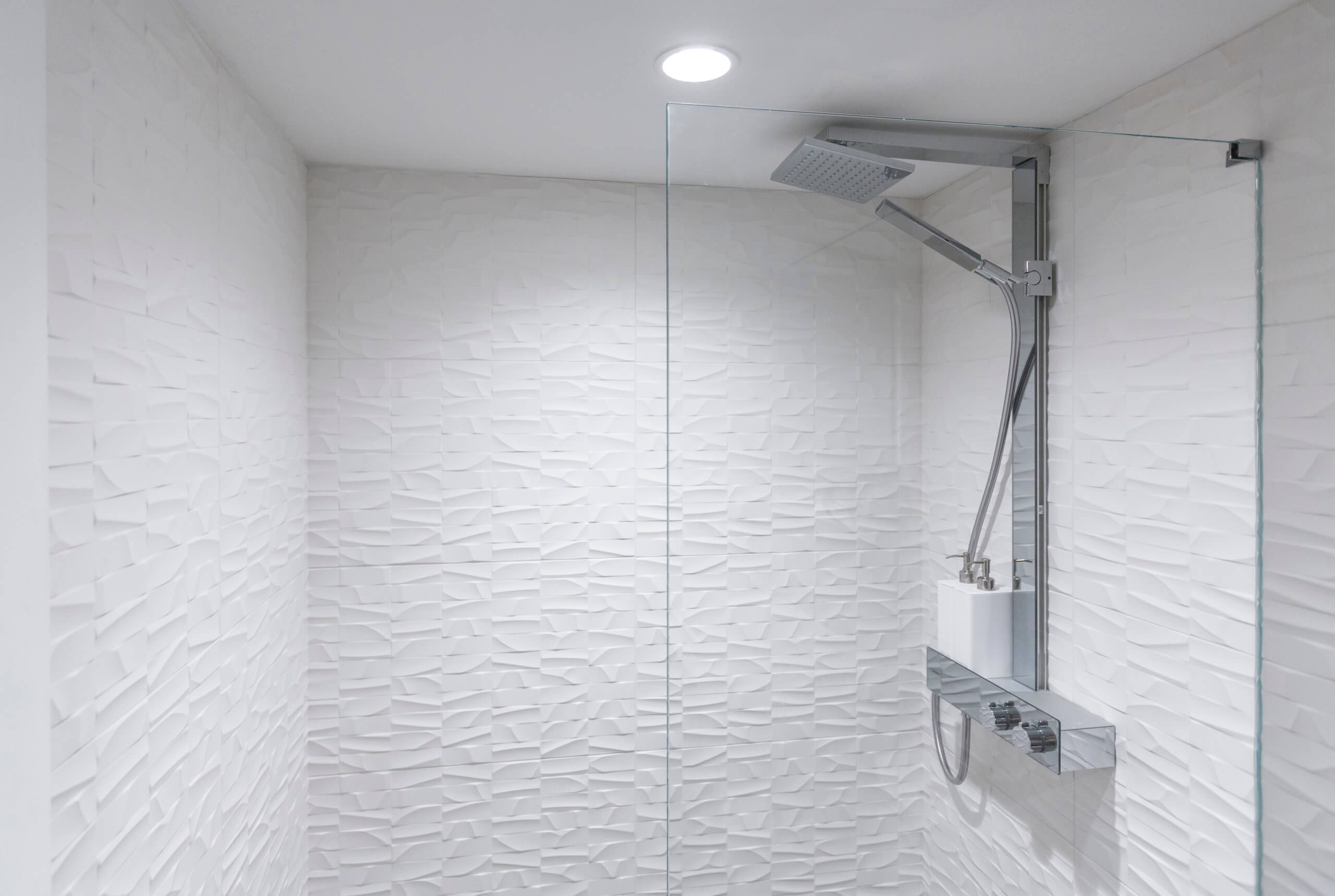 White textured tile and glass shower. Modern design by premier Cincinnati interior designer, RM Interiors.